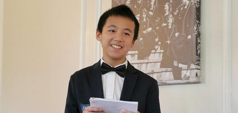 A young Chase Collegiate student in a tuxedo gives a speech.